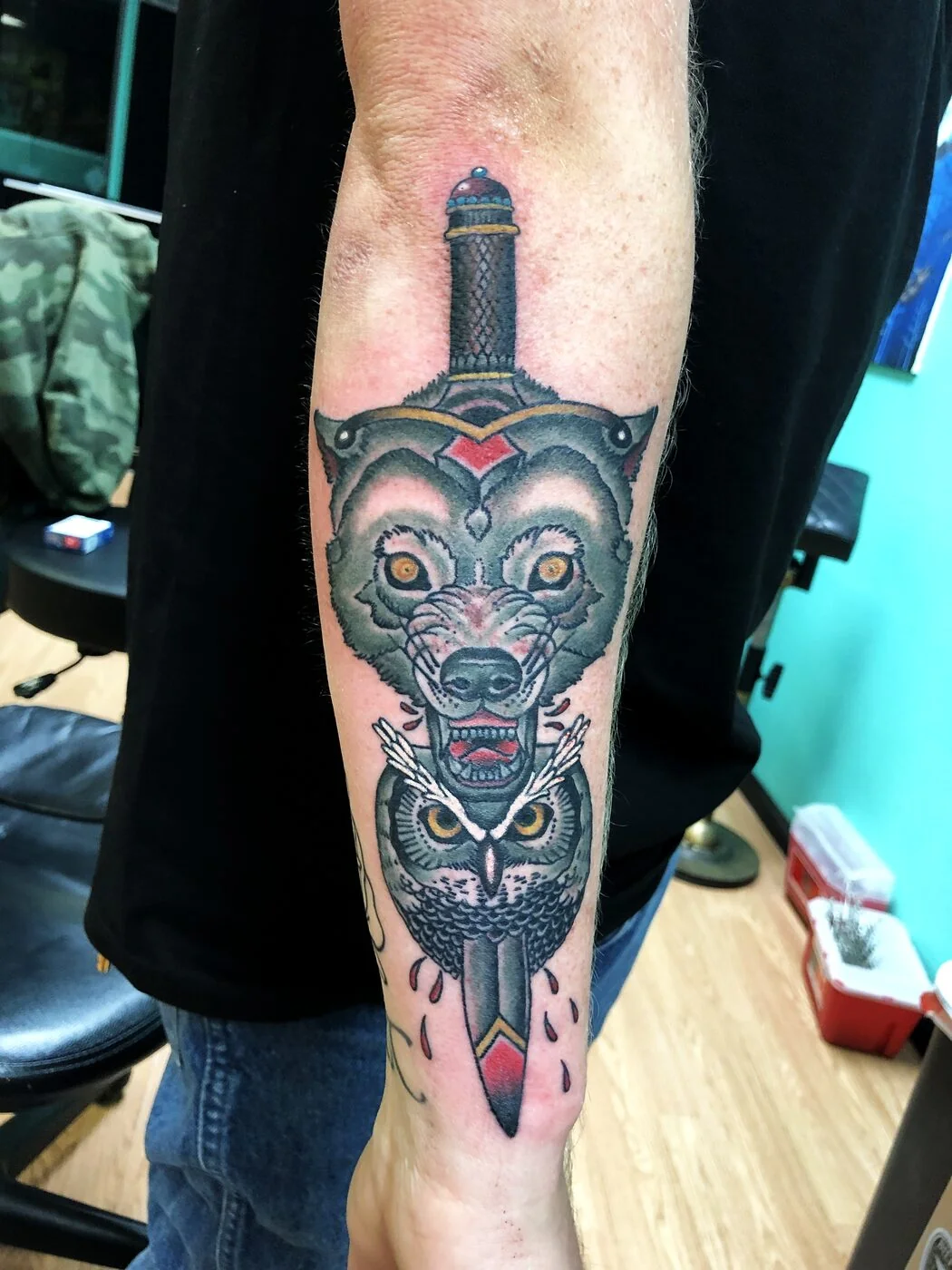 American Traditional wolf and owl sharing a dagger tattoo on forearm by 2bit (Chris Curren) at Lost at Sea Tattoo, Chinatown, Honolulu American Traditional wolf and owl sharing a dagger tattoo on forearm by 2bit (Chris Curren) at Lost at Sea Tattoo, Chinatown, Honolulu