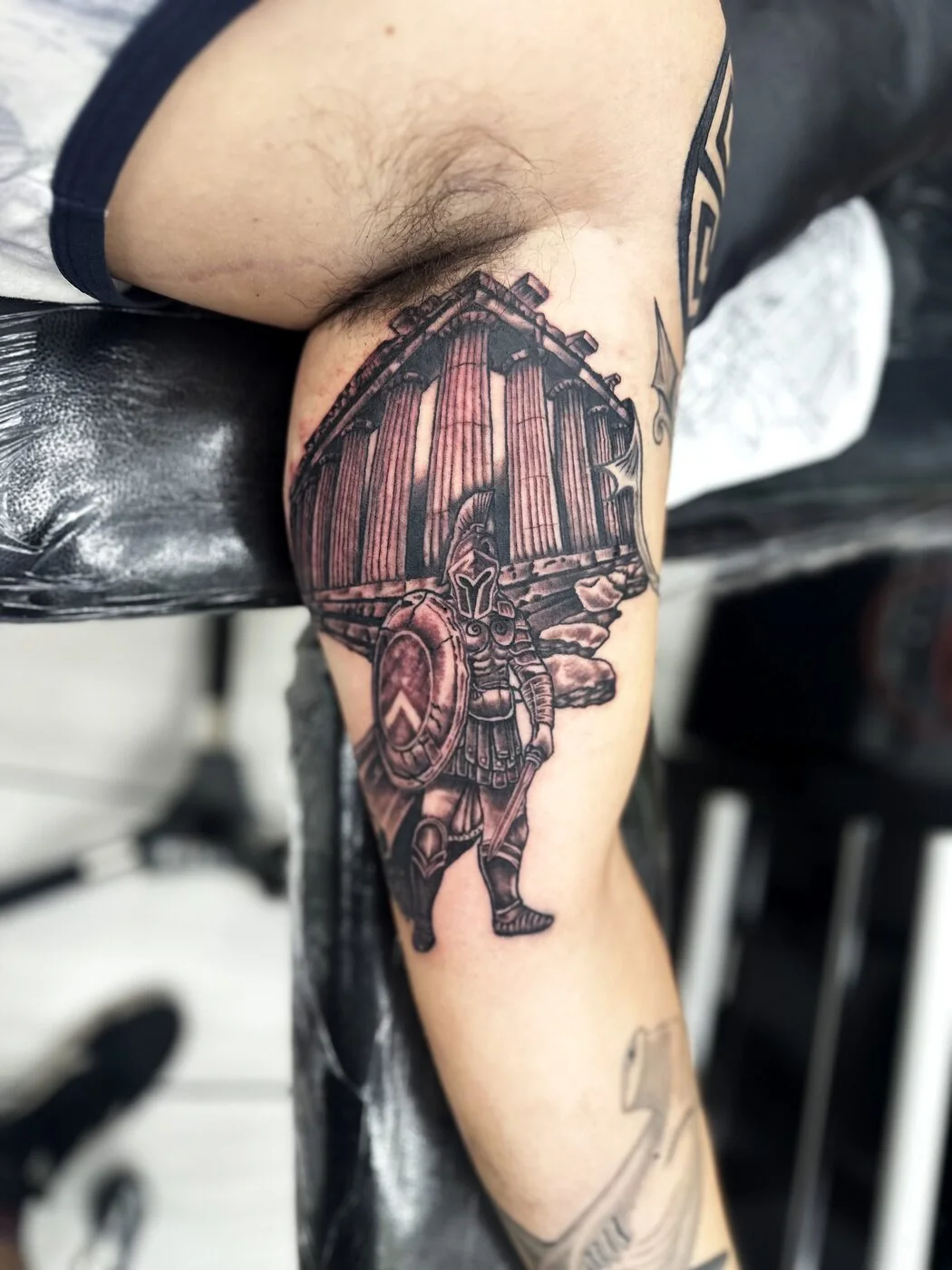 Black & Grey Spartan warrior with shield in front of Greek temple tattoo on bicep by 2bit (Chris Curren) at Lost at Sea Tattoo, Chinatown, Honolulu Black & Grey Spartan warrior with shield in front of Greek temple tattoo on bicep by 2bit (Chris Curren) at Lost at Sea Tattoo, Chinatown, Honolulu
